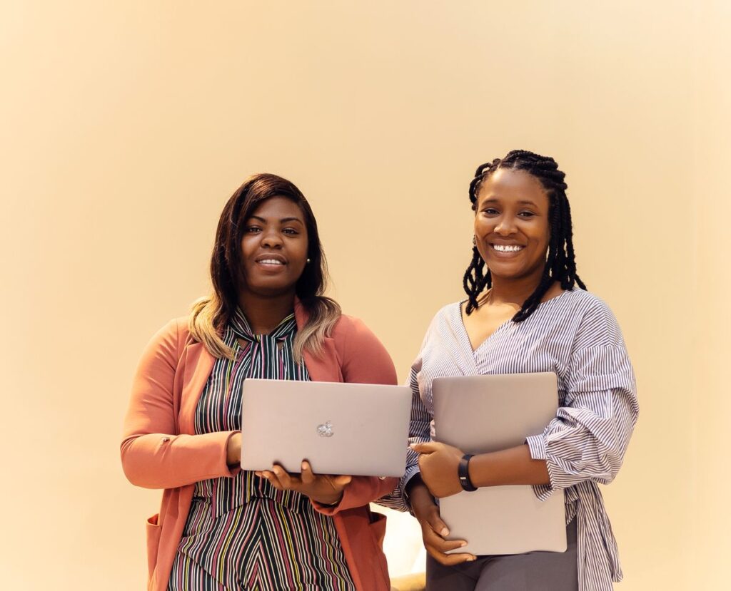Two African women founders working on laptops in a Lagos startup office