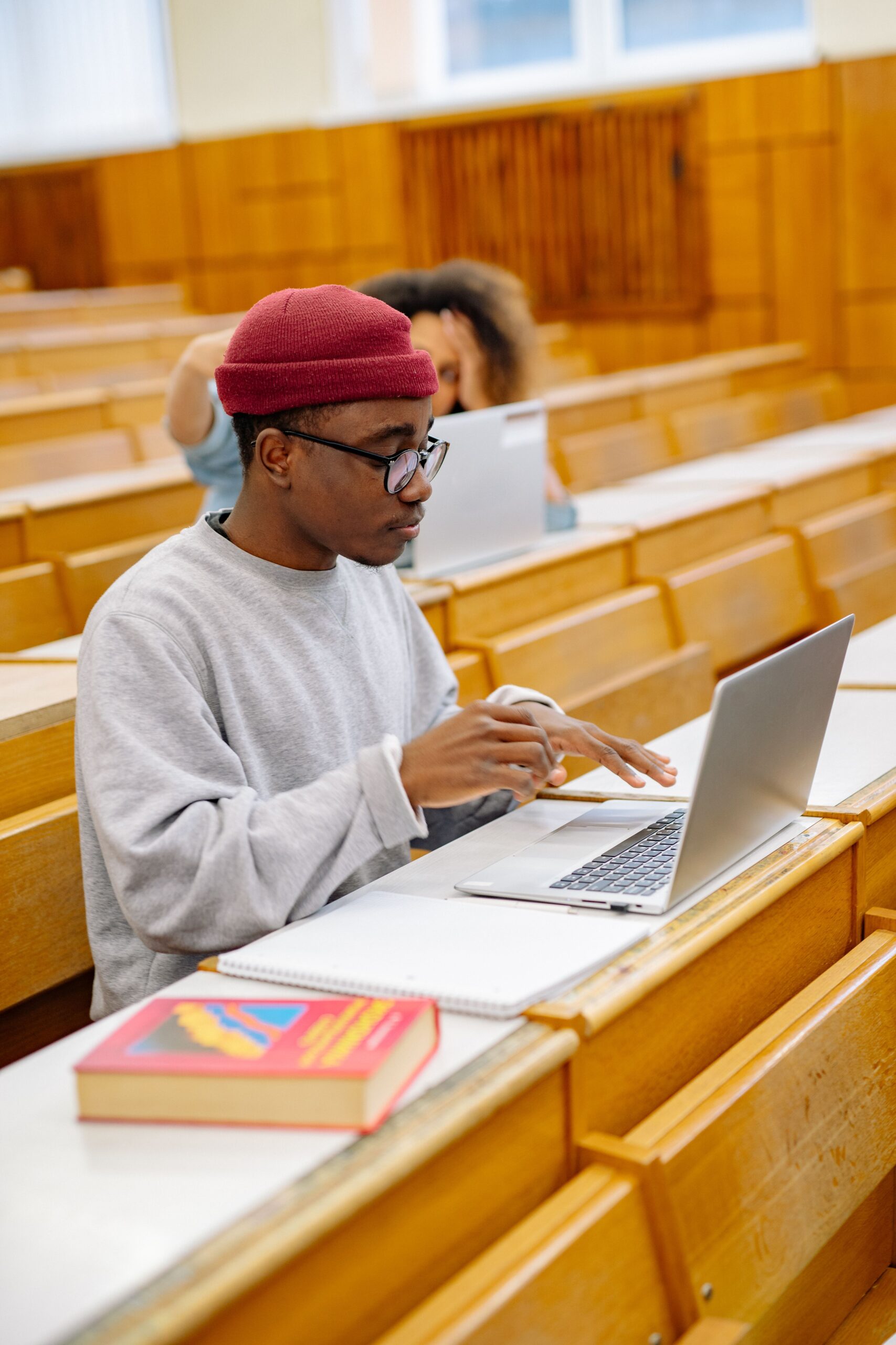Student taking an online English test on a laptop in a university lecture hall