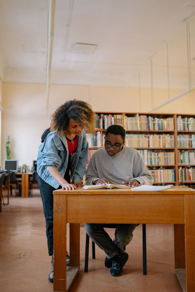 Two postgraduate students working through textbooks together in a university library
